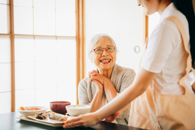 Caregiver serving a meal to an elderly client at home